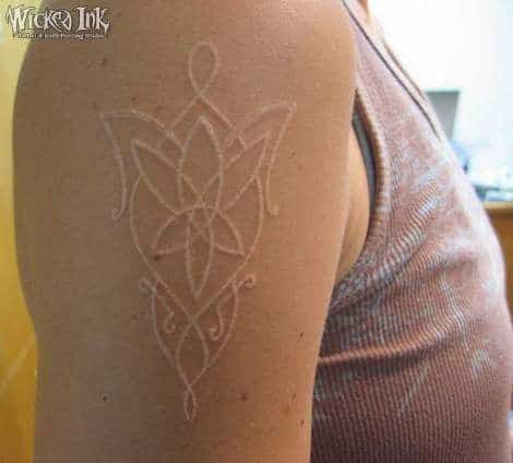 Tatuagem branca no braço de diversas linhas simétricas entre si
