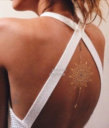 Tatuagem branca de uma mandala parecida com o sol bem no centro das costas de uma mulher