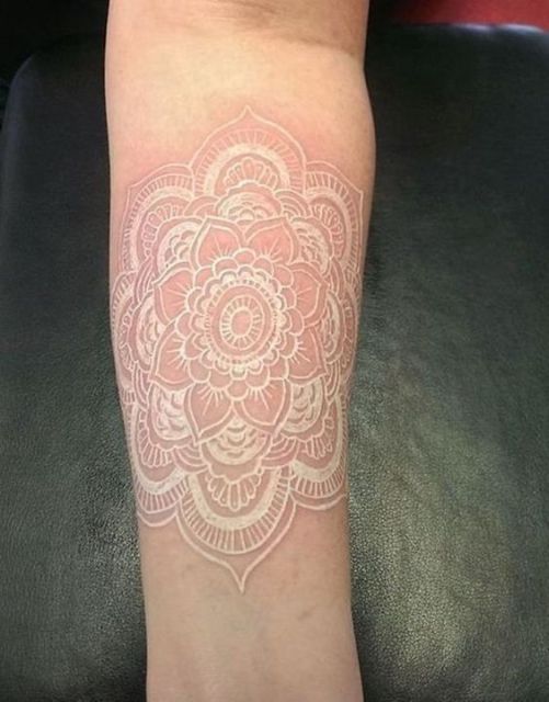 Tatuagem branca de uma mandala com uma flor no centro