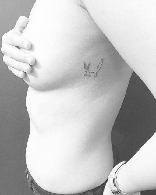 Tatuagem da raposa do Pequeno Príncipe bem pequena nas costelas de uma mulher