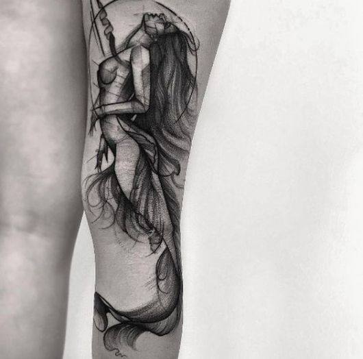 Tatuagem de uma sereia vista de lado olhando para cima feita em preto e branco