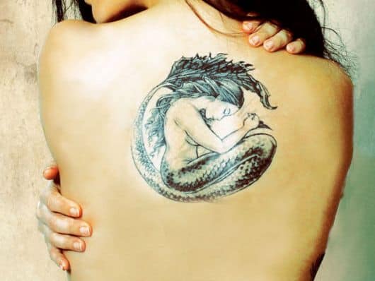 Tatuagem no centro das costas de uma sereia em posição fetal feita em preto e branco