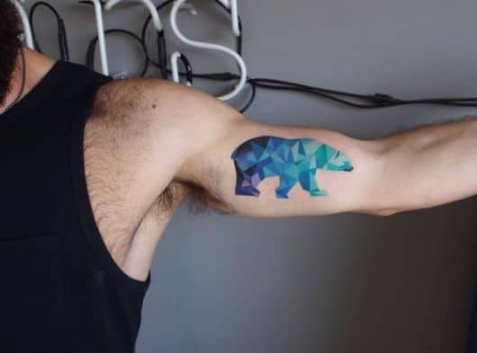 Tatuagem na parte interna do braço de um urso polar caminhando pintado de diferentes tons de azul