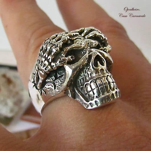 Modelo usa anel de caveira na cor prata com detalhes lapidados em furinhos.