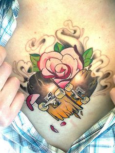 Tatuagem colorida de dois shapes partidos formando um coração com uma rosa entre eles.