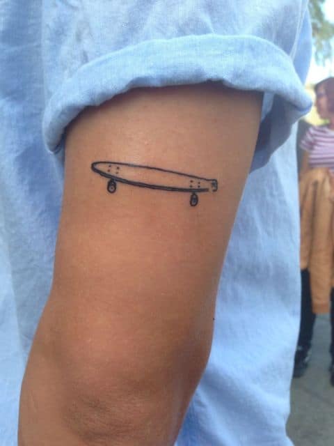 Tatuagem no braço de um longboard minimalista