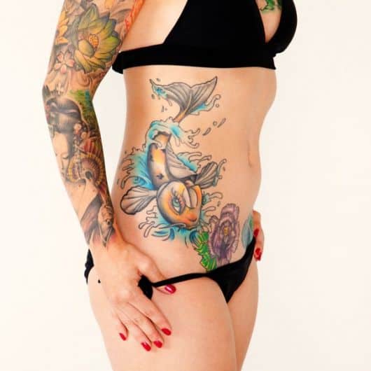 Tatuagem de uma carpa nadando feita na costela de uma mulher 