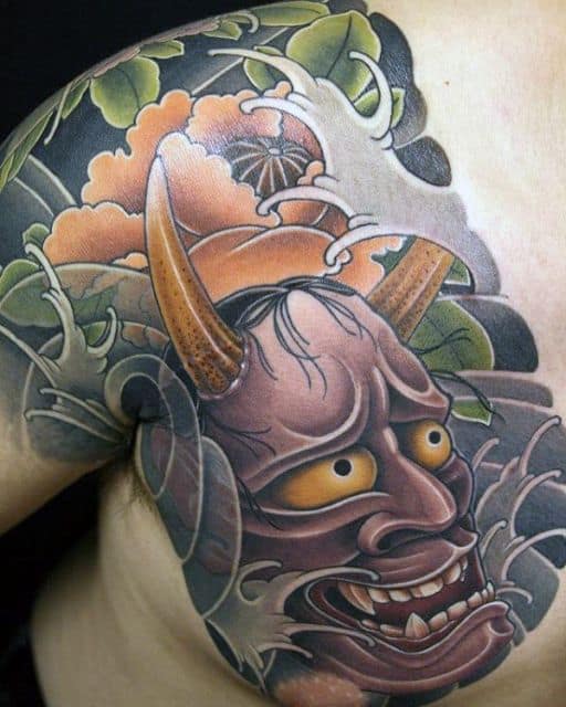 Tatuagem no peito de uma máscara hannya com muitos detalhes a sua volta.