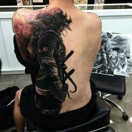 Tatuagem que cobre metade das costas de um homem. A tattoo é de um samurai feito em preto e branco com uma armadura muito bem feita.