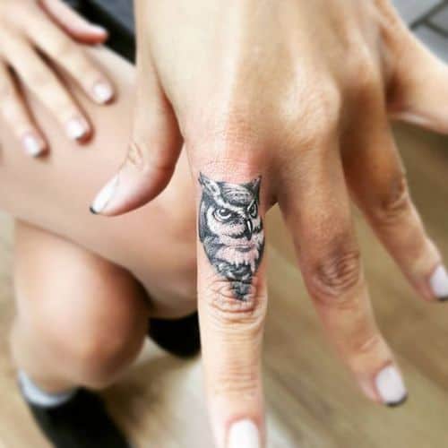 Tatuagem no dedo indicador do rosto de uma coruja bem simples