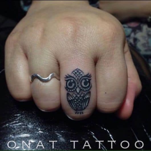 Tatuagem no dedo médio de uma coruja simples com os olhos muito grandes