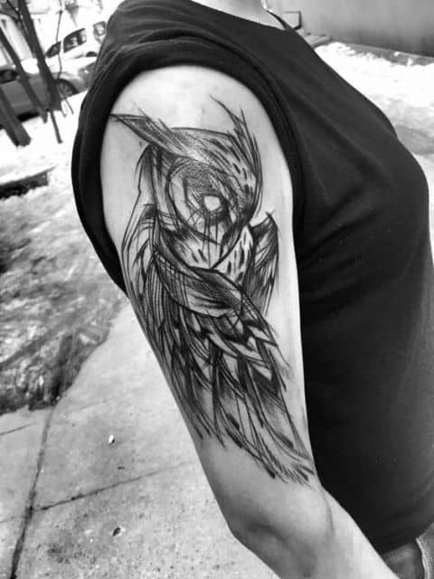 Tatuagem no braço com o desenho de uma coruja similar a um esboço. Ela está com as asas baixas e olhando para baixo. 
