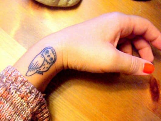 Tatuagem na parte lateral do pulso com o desenho de uma coruja simples vista de lado