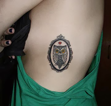 Tatuagem na costela de uma mulher com uma coruja simples dentro de um espelho. 