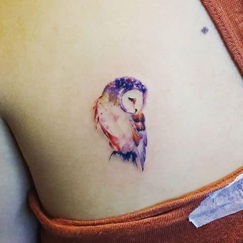 Tatuagem pequena na costela com o desenho de uma coruja pintada de aquarela 