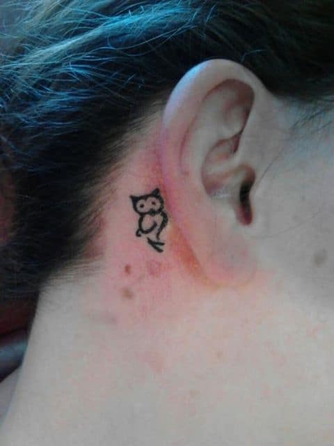 Tatuagem da silhueta de uma coruja feita atrás da orelha 