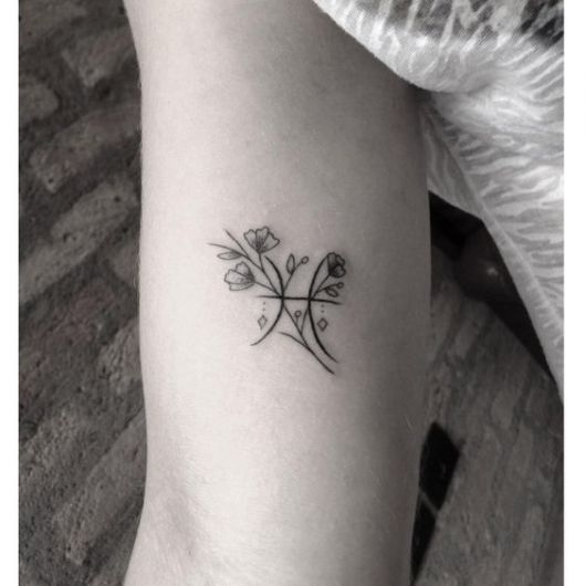 Tatuagem do símbolo do signo de peixes ornamentada com flores delicadas 