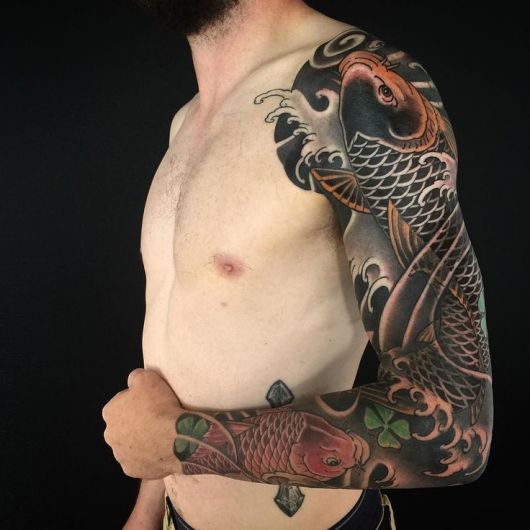 Tatuagem de carpa no estilo oriental cobrindo o braço inteiro de um homem 