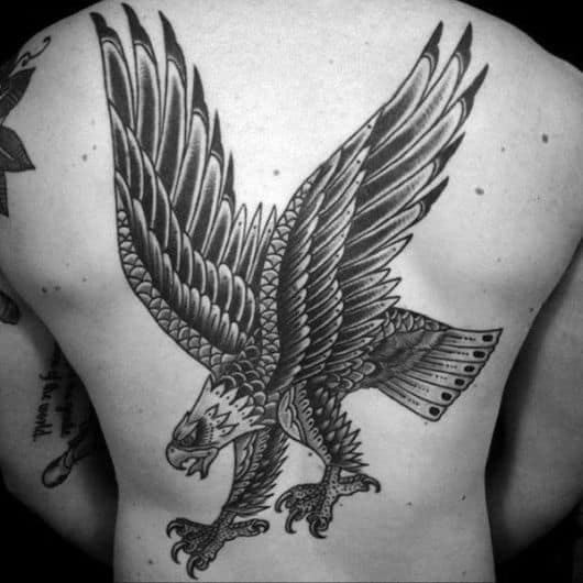 Tatuagem de uma águia em posição de ataque feita no estilo tradicional cobrindo grande parte das costas de um homem