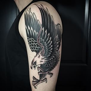 Tatuagem grande de águia no ombro com ela em posição de ataque e as asas para cima 