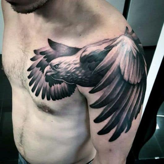 Tatuagem no ombro e parte do peito de um homem com o desenho de uma águia voando com as asas muito grandes
