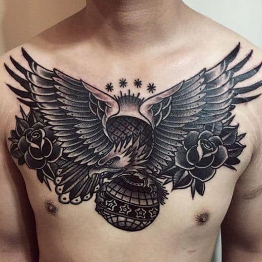 Tatuagem grande e escura no peito de um homem de uma águia com as asas abertas olhando para o lado