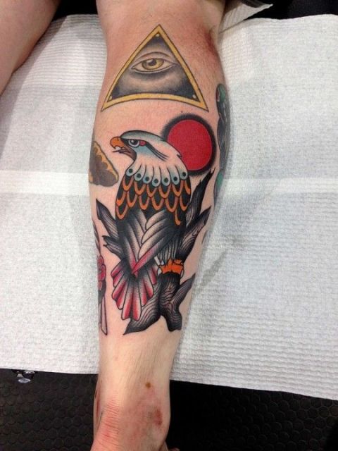 Tatuagem na panturrilha de uma águia vista de costas feita com cores vivas como vermelho e laranja  