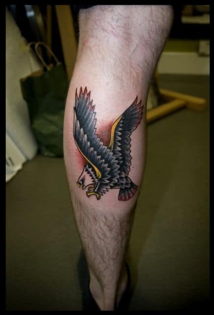 Tatuagem pequena na panturrilha do desenho de uma águia em posição de ataque 