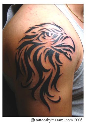 Tatuagem tribal no ombro feita somente com traços escuros mostrando a cabeça de uma águia 