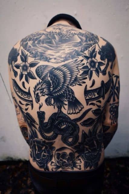 Foto das costas de um homem com muitas tatuagens. No centro há a tattoo uma águia vista de perfil.
