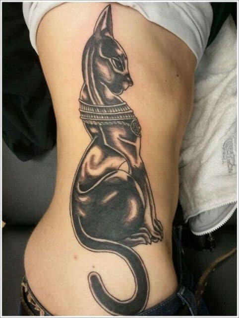Tatuagem de um gato egípcio sentado feito na costela de uma mulher. 