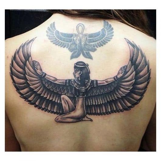 Tatuagem grande nas costas de uma mulher da deusa Isís sentada no chão com os braço estendidos. 