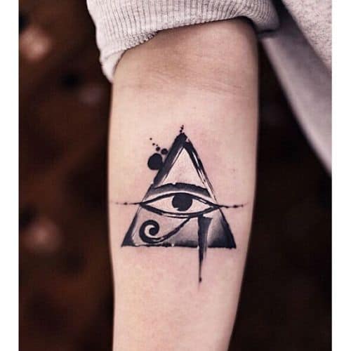 Tatuagem feita no antebraço com o desenho do olho de hórus dentro de um triângulo 