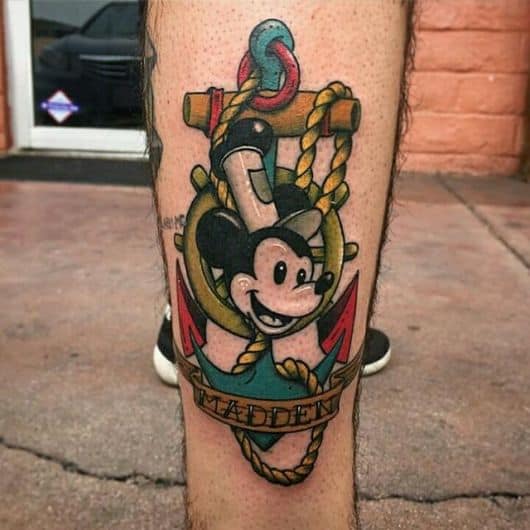 Tatuagem na lateral da canela de um mastro com o rosto do mickey logo a frente. 