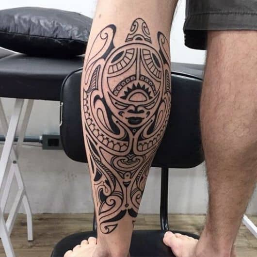 Tatuagem maori na canela de um homem com o desenho de diversas formas que se assemelham a uma tartaruga.