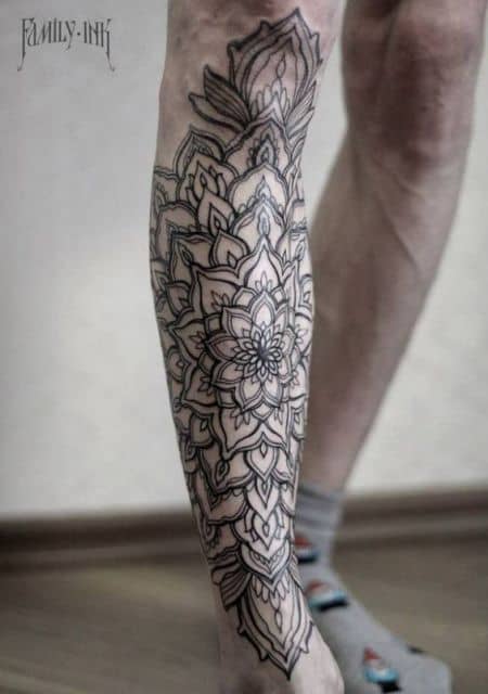 Tatuagem na canela de uma manda que começa com o formato de uma flor e vai se expandindo em outras formas. 