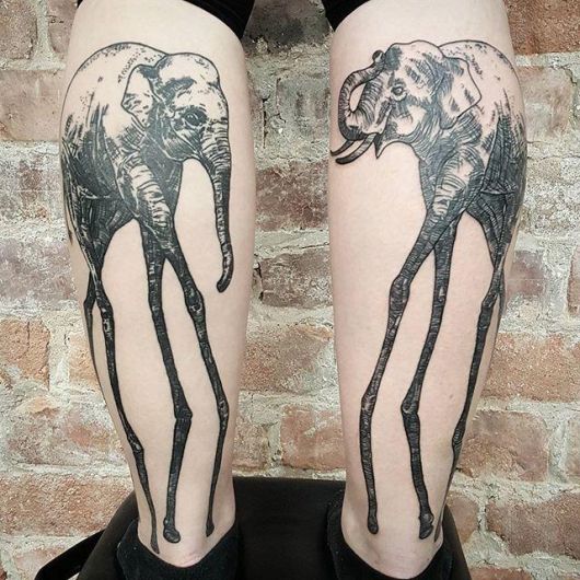 Duas tatuagens, uma em cada panturrilha. Em cada uma há um elefante com as patas de girafas como na obra de Salvador Dalí. 