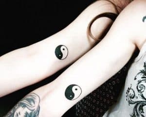Tatuagem de um Yin Yang simples no braço de uma mulher, bem entre a divisão do braço e o antebraço.