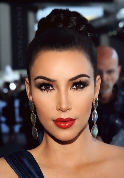 Kim Kardashian com batom vermelho e brincos compridos.