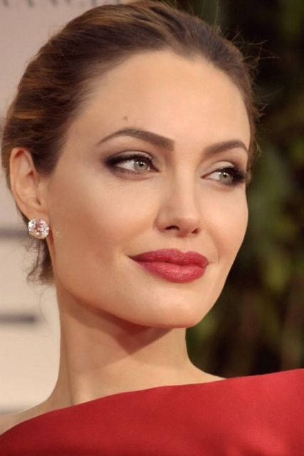 Angelina Jolie com cabelo preso e sobrancelha arqueada marcada.