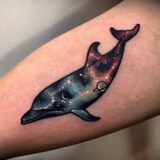 Tatuagem de um golfinho com seu interior pintado para simular o universo. 