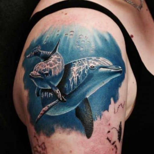 Tatuagem realista de dois golfinhos nadando lado a lado no mar profundo. 