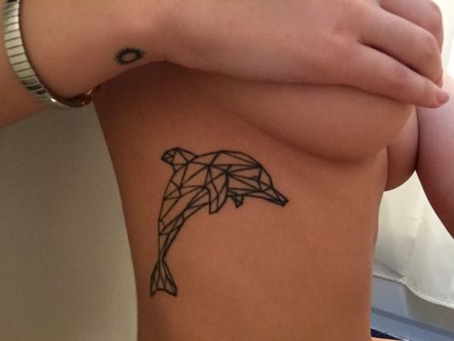 Tatuagem na costela da silhueta de um golfinho feita a partir de diversas linhas retas. 