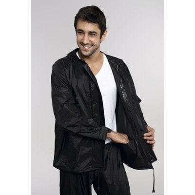 Foto de um homem sorrindo vestindo uma jaqueta de nylon preta enquanto coloca uma das mãos no bolso interno da jaqueta. 