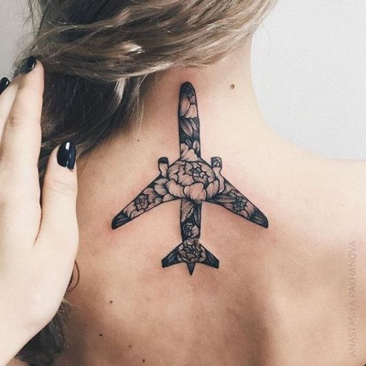 Tatuagem de um avião preenchido com diversas flores no centro das costas de uma mulher. 