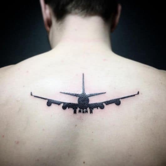 Tatuagem de silhueta de um avião decolando preenchido de preto no centro das costas de um homem. 