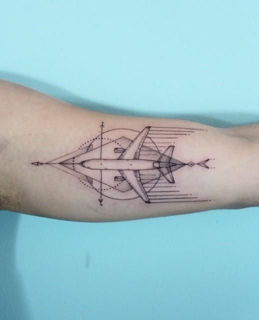Tatuagem de um avião visto de cima sincronizado com um losango no qual está inserido.  
