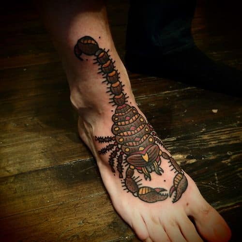 Tatuagem de escorpião no pé feita com cores vivas cobrindo parte da canela.