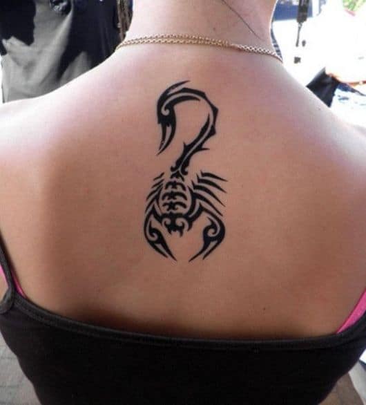 Tatuagem de escorpião feita no centro das costas de uma mulher usando o estilo tribal. 