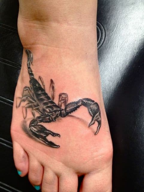 Tatuagem de escorpião em tons de preto feita no peito do pé. 